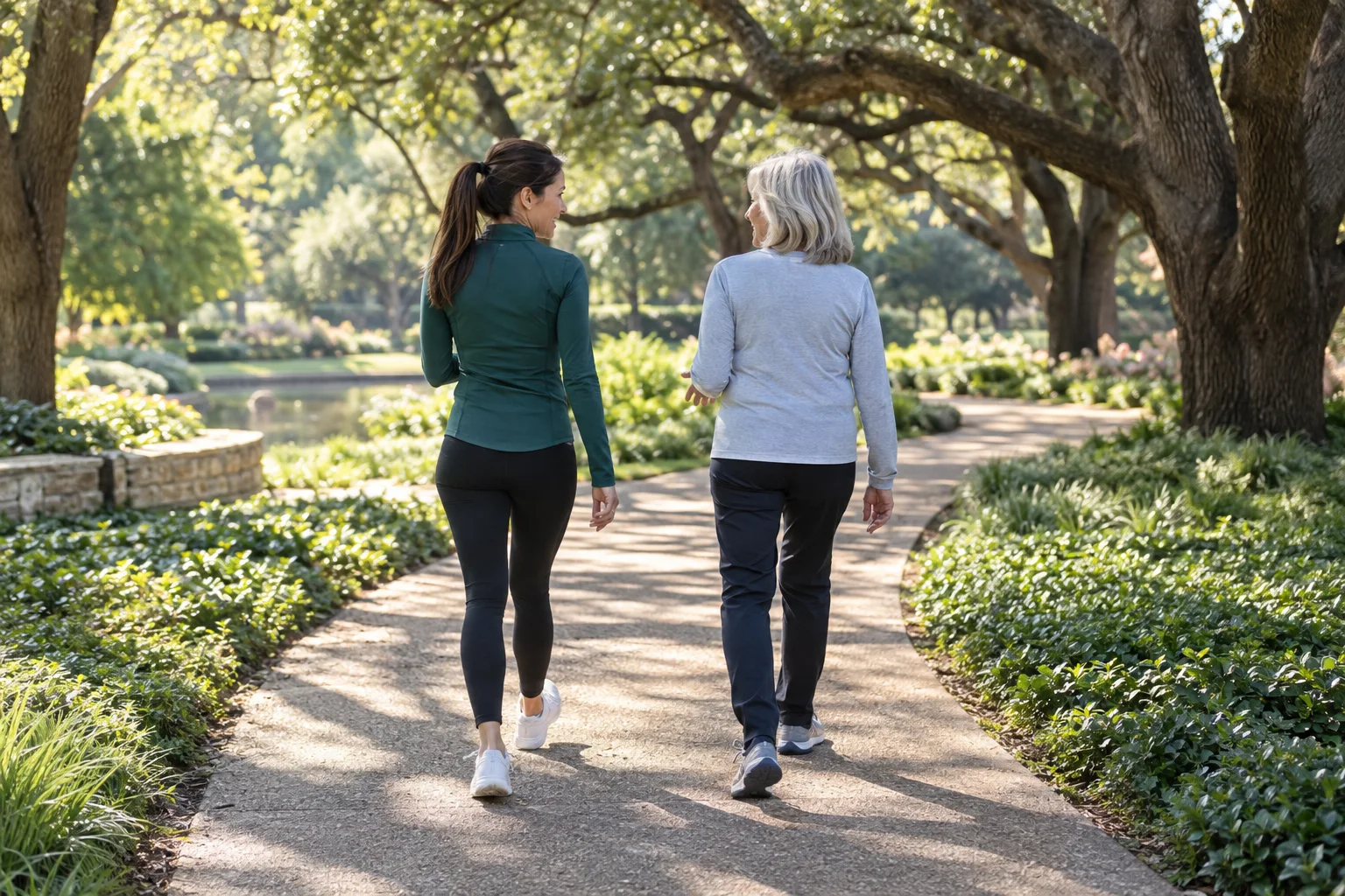 Nicole Flores and an older companion walking together beneath mature trees in a Dallas park
